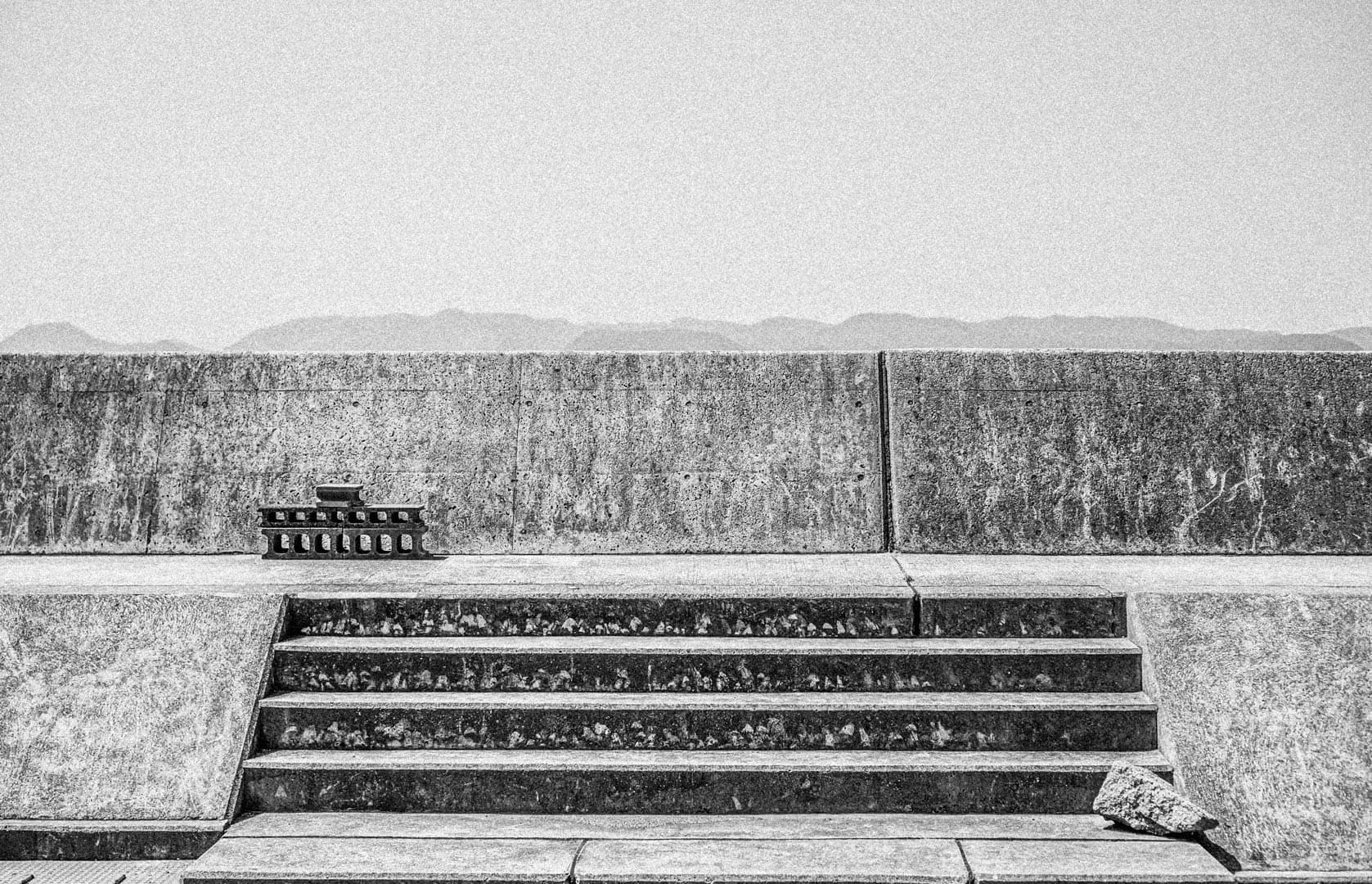 Upclose Photgraph of a Staircase-ledge above which Looms a Ridge of Mountains