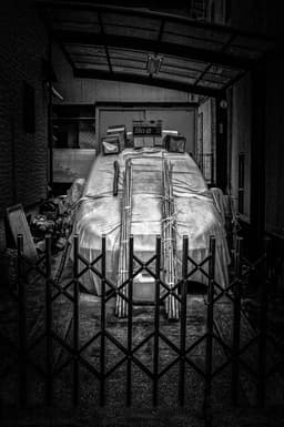 Photograph of a Car with A Tarp atop Held Down with Bamboo